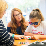 Nine-year-old Analeina Lugo reads with red-green bar filters with red-green filters on her glasses to help coordinate her eyes when viewing things up close.