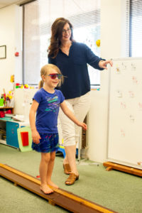 Teresa Richards, a certified optometric vision therapist, works with 6-year-old McKenzie Neufeld on an activity that combines balance and vision.