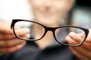 Image of blurred out woman holding out glasses that are in focus.