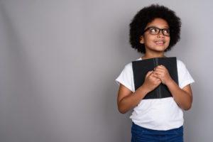 Child wearing glasses and holding a book