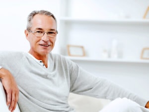 Mature man using sitting on the sofa at home and looking at the camera.