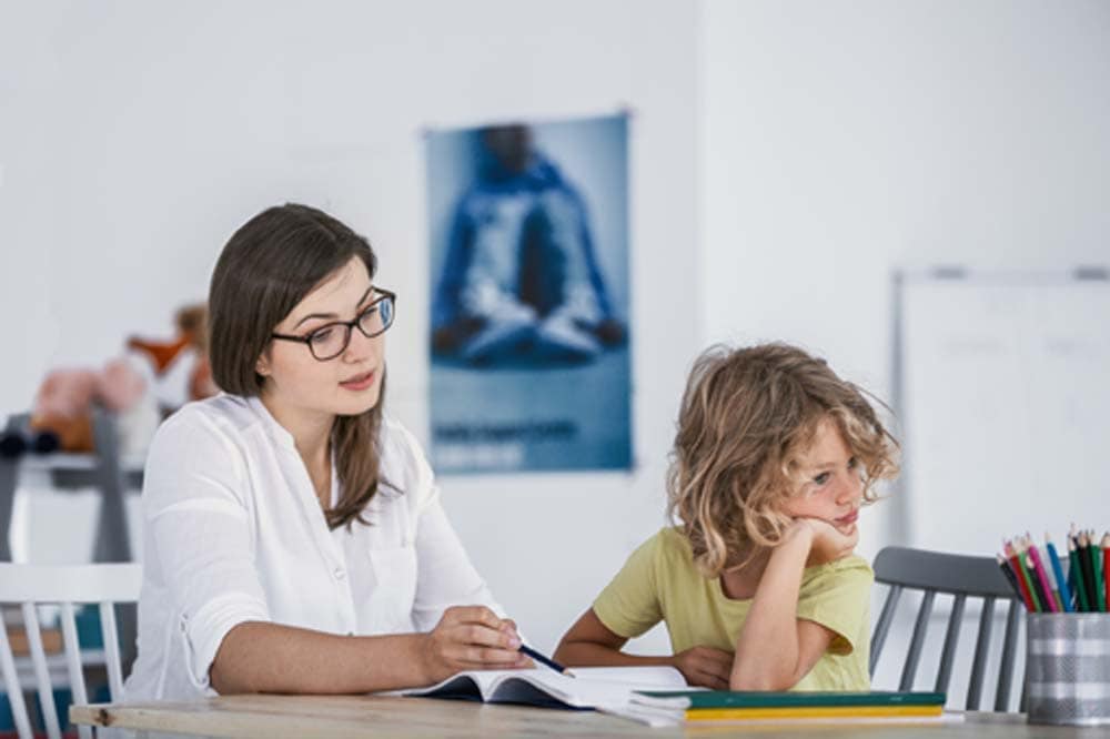 A bored child refusing to cooperate with his private teacher while doing homework. A bored child refusing to cooperate with his private teacher while doing homework.